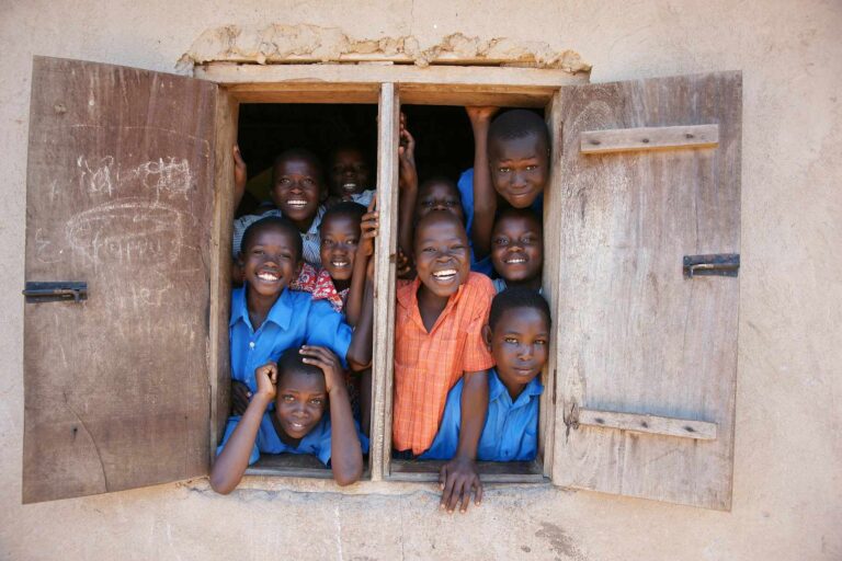 Children smiling and peering out of a window